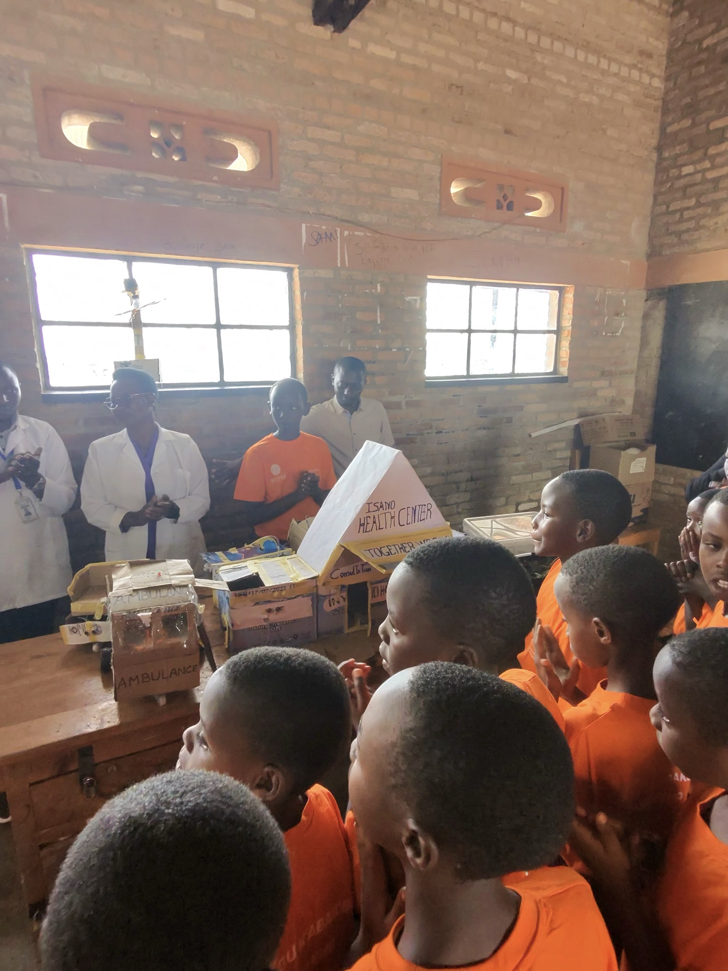 Students presenting a handbuilt robotics project — a model ambulance and health centre — in Rwanda
