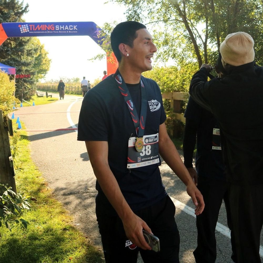 A finisher wearing the navy participant shirt and medal at the finish arch