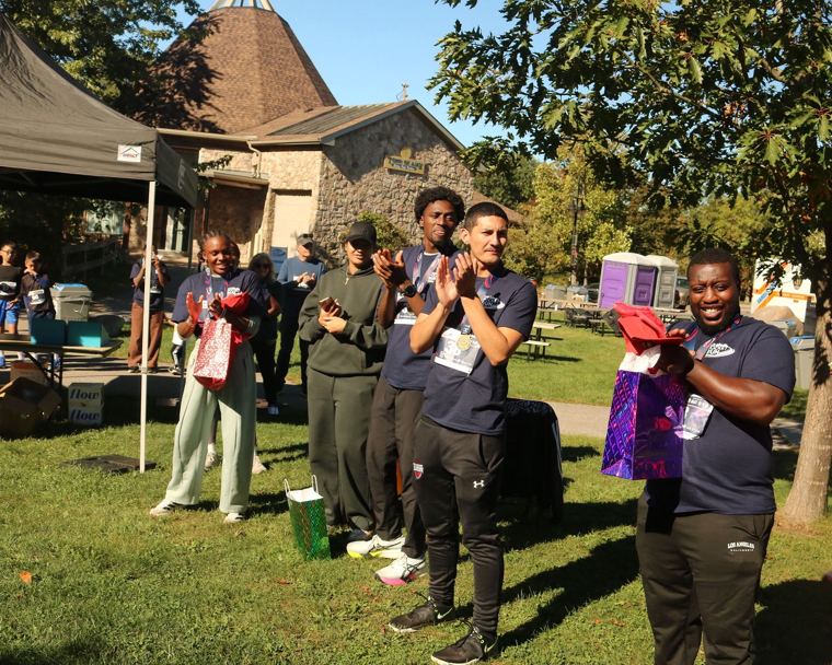 Participants and volunteers applauding at the gift bag table